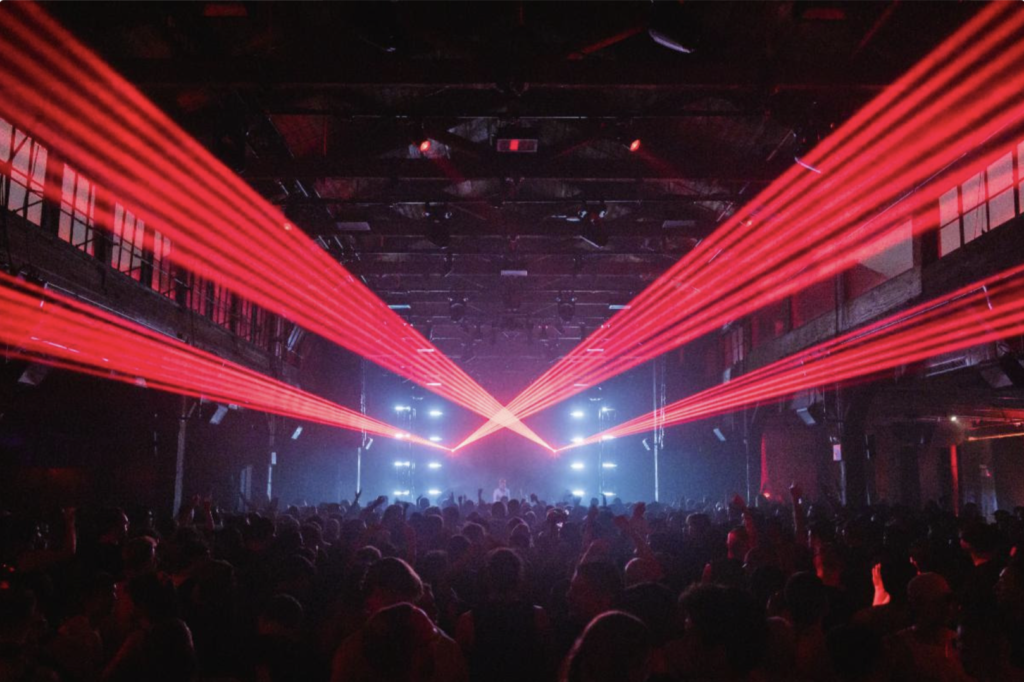 Red laser light show during WIRE Festival at Knockdown Center, NYC, with a packed crowd